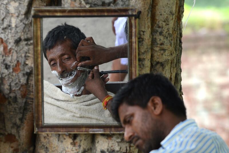 An Indian barber shaves a customer at a road side stall in Jalandhar. Shammi Mehra/AFP