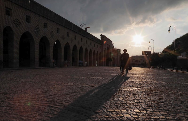 A man walks in a deserted street in front of the Erbil citadel in Iraq.   AFP
