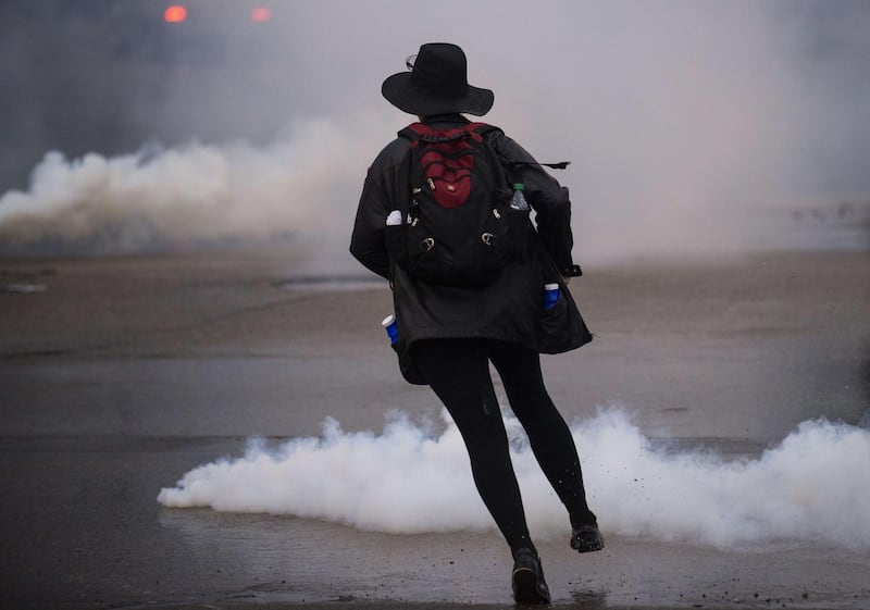 A protesters runs through tear gas while demonstrating against the death of George Floyd outside the 3rd Precinct Police Precinct in Minneapolis, Minnesota. AFP