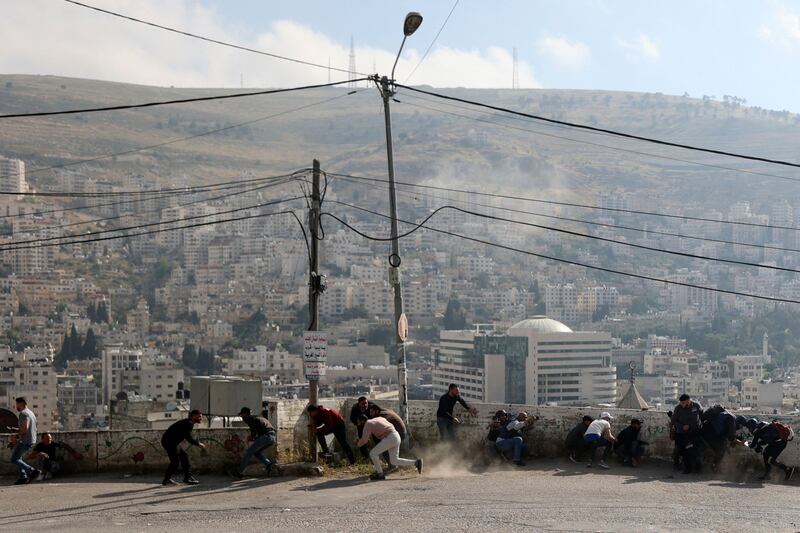 Palestinian take cover during a raid in the West Bank city of Nablus, on May 9, 2023.  AFP