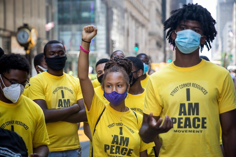 Volunteers from Street Corner Resources stand while protesters, not pictured, shout slogans during the painting of a 'Black Lives Matter' mural along Fifth Avenue in front of Trump Tower in New York. Bloomberg