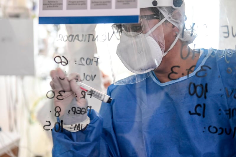 Healthworkers writes notes on a glass as she checks apatient at the Intensive Care Unit at  the Pablo Tobon Uribe Hospital, in Medellin, Colombia. AFP