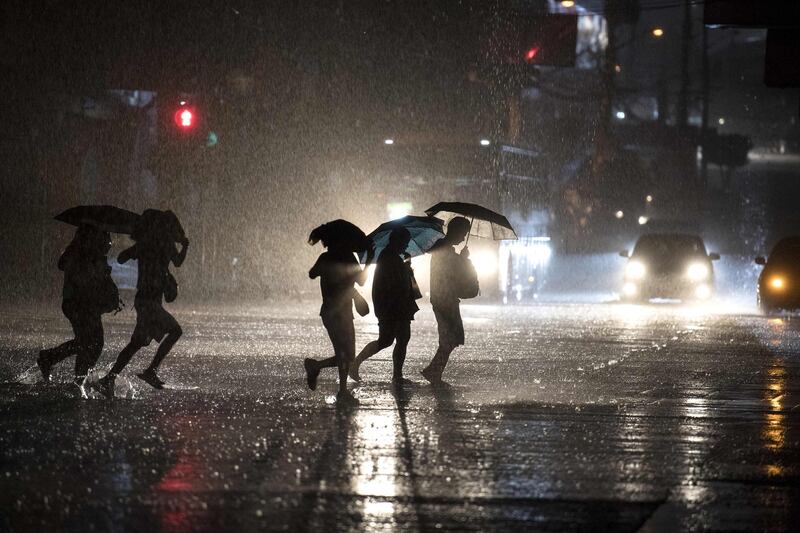 People cross a road during heavy rain caused by Typhoon Maliksi in Manila. Noel Celis / AFP