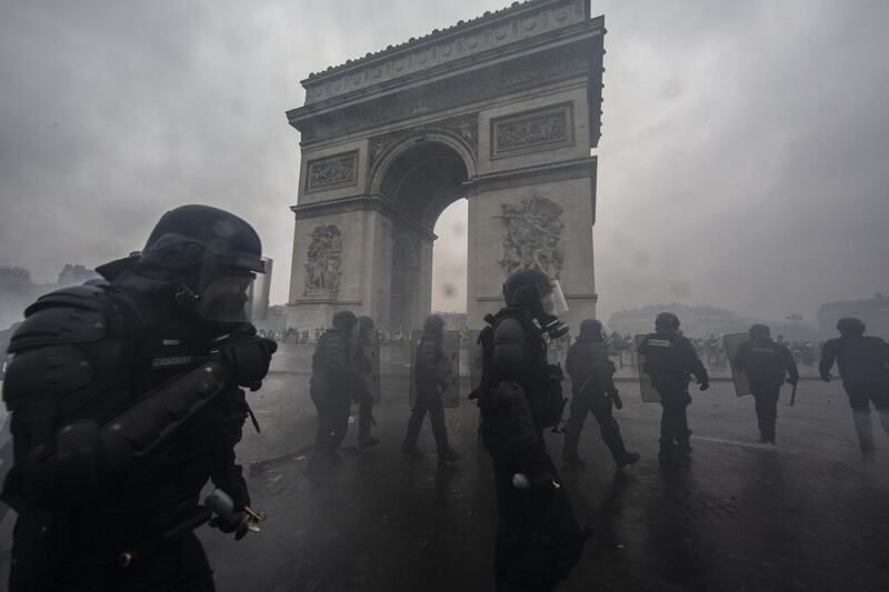 Teargas surrounds riot police as they clash with protesters near the Arc de Triomphe in Paris. Getty Images