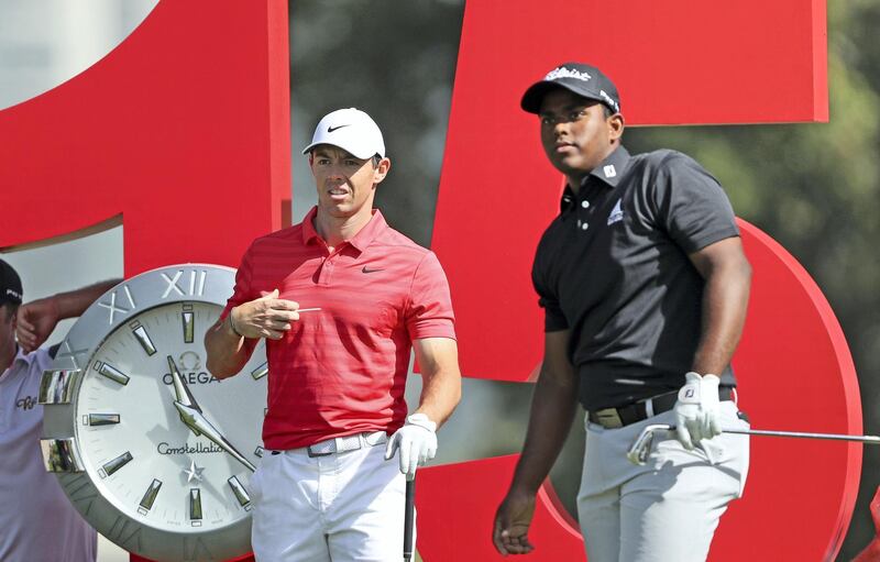 DUBAI, UNITED ARAB EMIRATES - JANUARY 23:  Rayhan Thomas of India walks is watched by Rory McIlroy of Northern Ireland on the 15th hole during a practice round together as a preview for the Omega Dubai Desert Classic on the Majlis Course at The Emirates Golf Club on January 23, 2018 in Dubai, United Arab Emirates.  (Photo by David Cannon/Getty Images)