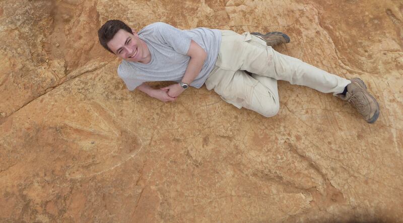 Fabien Knoll, an honorary senior research fellow at the University of Manchester, lies next to  footprints belonging to the Kayentapus ambrokholohali dinosaur in Lesotho in October 2017. AFP