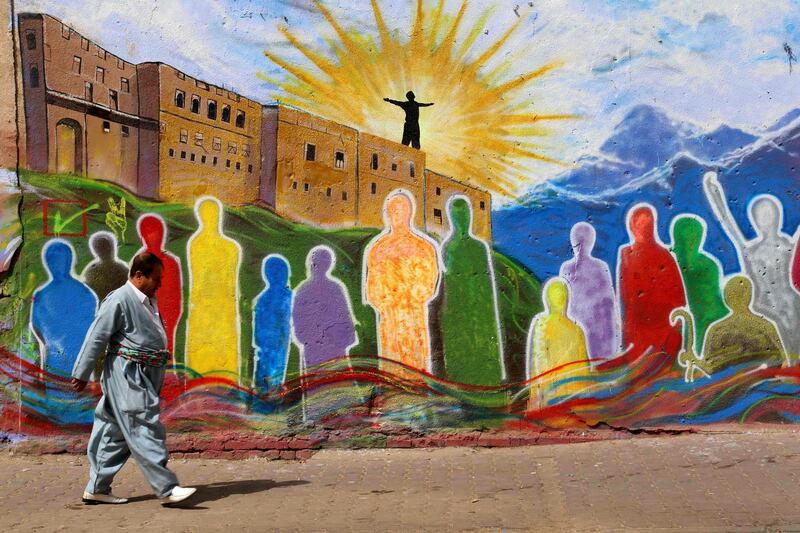 An Iraqi Kurdish man walks past a mural in the square in the citadel in Arbil, the capital of the autonomous Kurdish region of northern Iraq, on September 26, 2017, the day after Iraq's Kurds defied widespread opposition to vote in a historic independence referendum. / AFP PHOTO / SAFIN HAMED