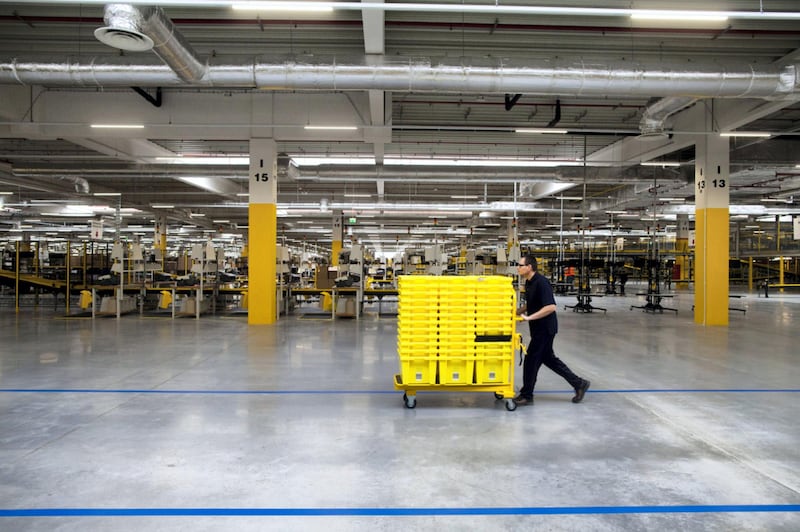 An employee pushes yellow product crates on a trolley across the work floor at the new Amazon Inc. fulfilment center on its official day of opening in Bielany Wroclawskie, Poland, on Tuesday, Oct. 28, 2014. The company announced on Monday that it's taking preorders for a streaming media stick that plugs into a TV, making it possible to watch a range of Internet video services. Photographer: Bartek Sadowski/Bloomberg