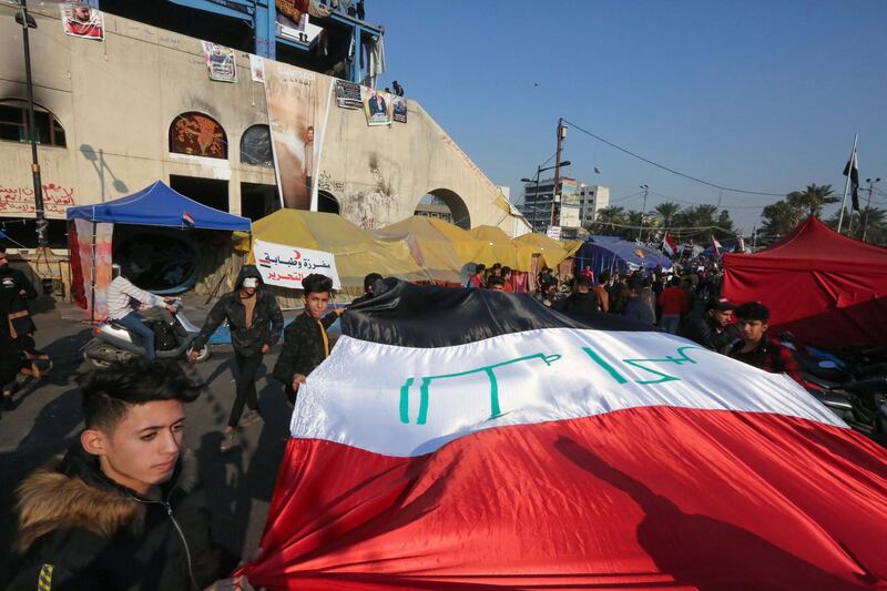 Iraqi anti-government protesters carry a large natioanl flag during ongoig demonstrations in the capital Baghdad's Tahrir square.  AFP