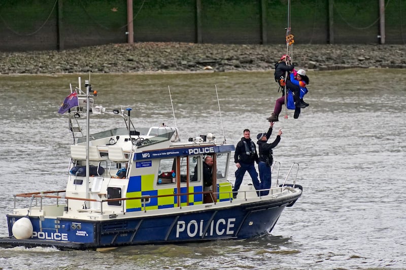 A protester from Extinction Rebellion is lowered into a police boat on the Thames. PA