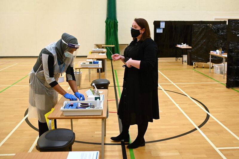 A teacher hands over a Covid-19 lateral flow test to another staff member in the sports hall of Park Lane Academy in Halifax. AFP