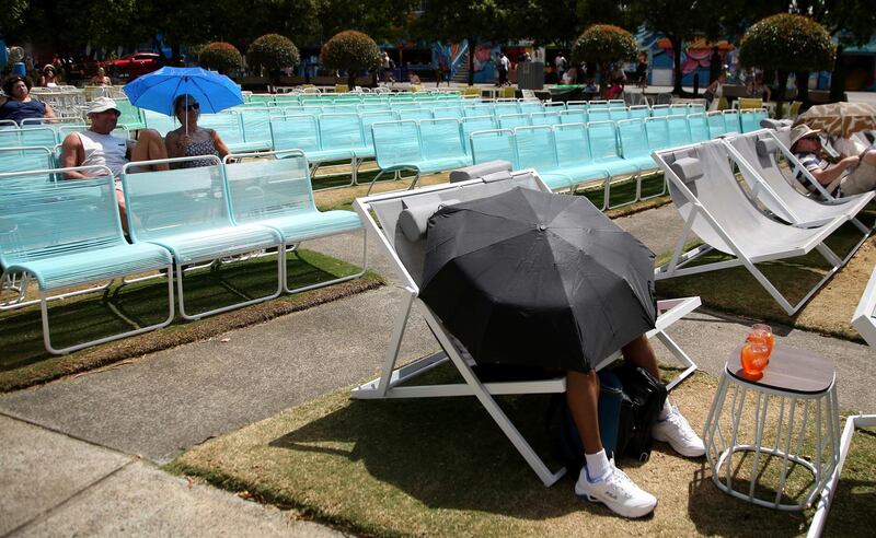 Spectators protect themselves from the heat with umbrellas as they watch tennis on a large video screen in Melbourne. AP Photo