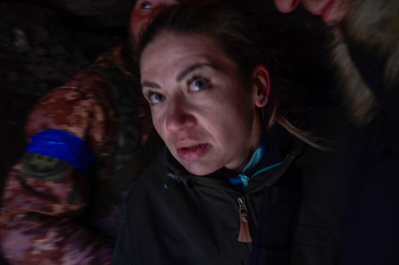 A woman takes cover in a military trench as a Russian jet fighter flies overhead, near the military school hit by Russian rockets the day before, in Mykolaiv. AFP