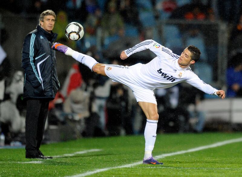 Real Madrid's Portuguese forward Cristiano Ronaldo (R) controls a ball next to Real Madrid's Chilean coach Manuel Pellegrini during a Spanish league football match against Getafe at Alfonso Perez stadium on March 25, 2010,  in Getafe near Madrid.  AFP PHOTO/JAVIER SORIANO.