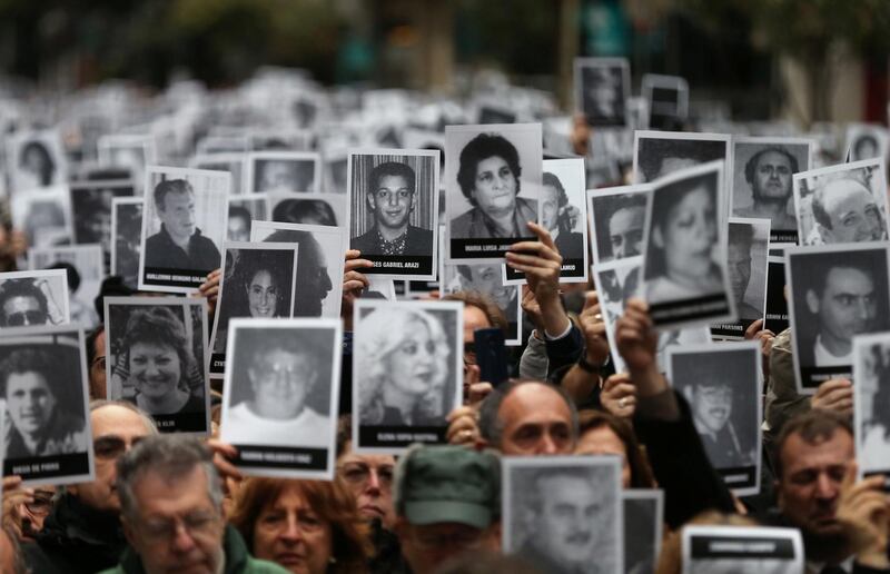 People hold images of the victims of the 1994 bombing attack on the Argentine Israeli Mutual Association (AMIA) community centre, marking the 25th anniversary of the attack, in Buenos Aires, Argentina, July 18, 2019. REUTERS/Agustin Marcarian