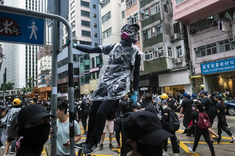 A demonstrator wearing a gas mask holds on to a signpost during a protest on Queens Road East in the Wan Chai district of Hong Kong. Bloomberg