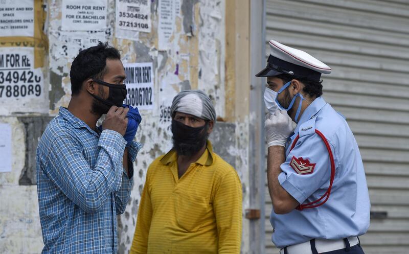 A Bahraini police officer instructs a foreign worker to wear his protective mask, in the old marketplace of the capital Manama.   AFP