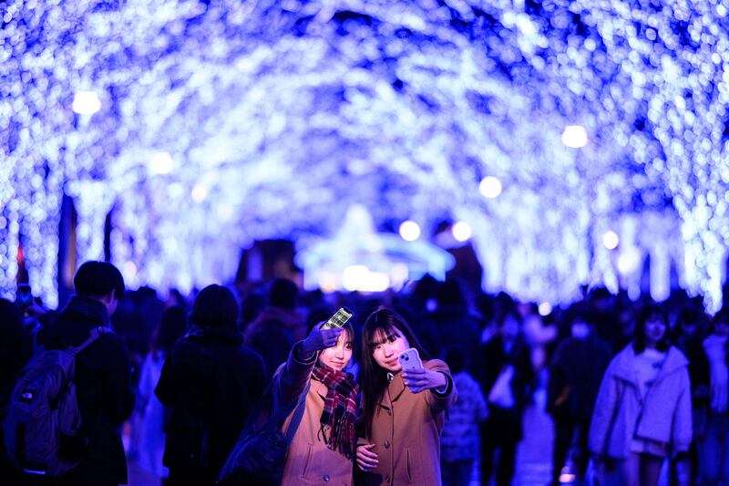 Revellers take pictures among the festive light installations in Tokyo's Shibuya district. AFP