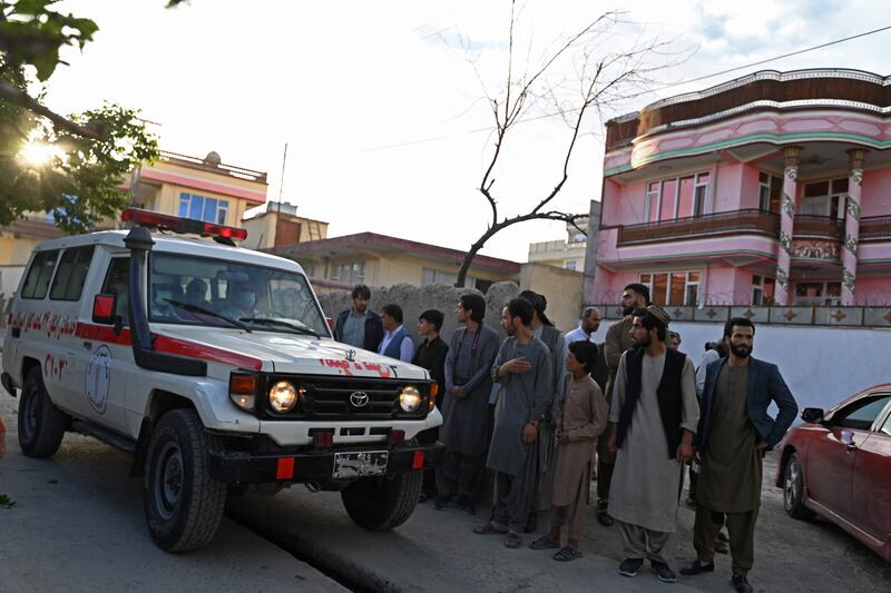 Onlookers stand next to an ambulance carrying victims near the site of a blast in Kabul. AFP