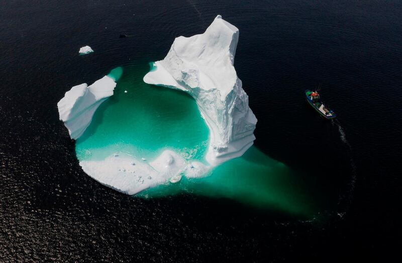 This aerial photo shows the boat of Captain Edward Kean passing an iceberg in Bonavista Bay in Newfoundland, Canada.  The abundance of icebergs, which continue to venture further into Canadian waters, has created a new form of tourism, iceberg sightseeing. In 2018, more than 500,000 tourists visited the province of Newfoundland, contributing nearly 570 million Canadian dollars (389 million euros) to the local economy, according to the estimates of the provincial government.  AFP