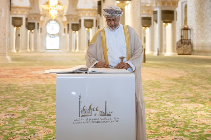 Sultan Haitham signs a guest book during a visit the Sheikh Zayed Grand Mosque
