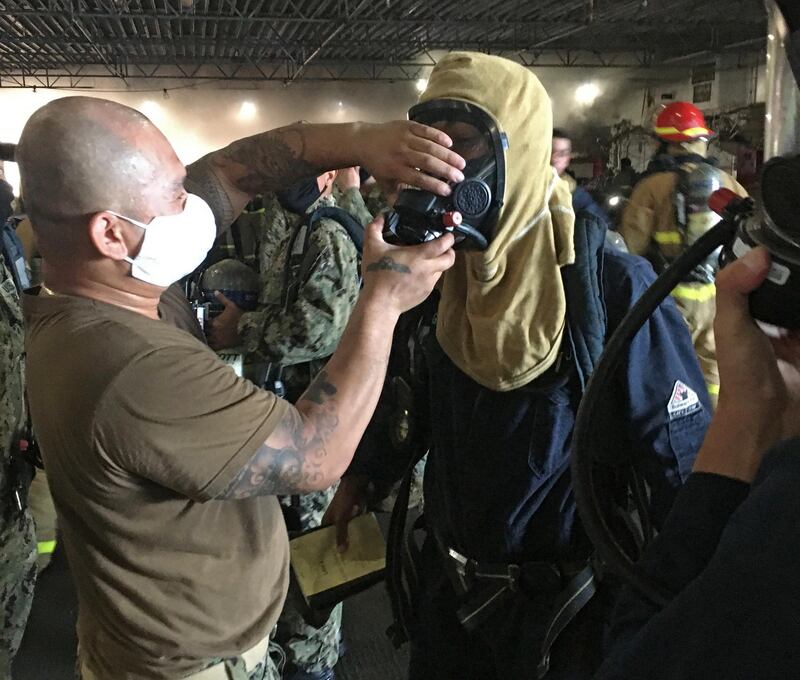 Sailors aboard the assault ship 'USS Bonhomme Richard' wear fire-fighting equipment to combat a blaze aboard the ship in San Diego, California, US.  EPA