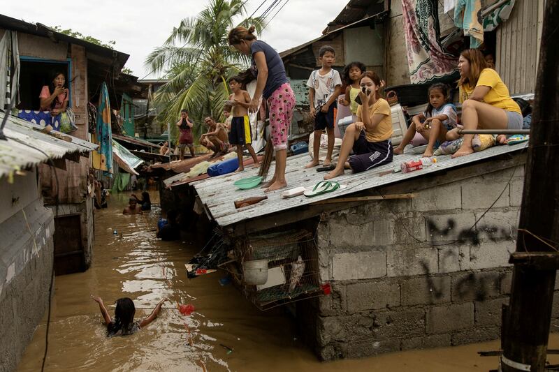 Residents wait on the roof of their homes for the flooding to subside after Super Typhoon Noru, in San Miguel in the  Philippines. Reuters