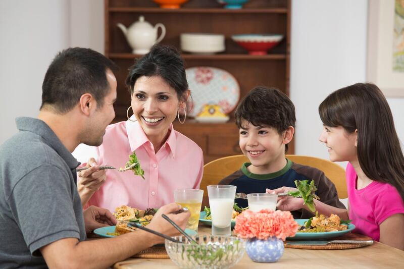 Hispanic family eating dinner together. Getty Images