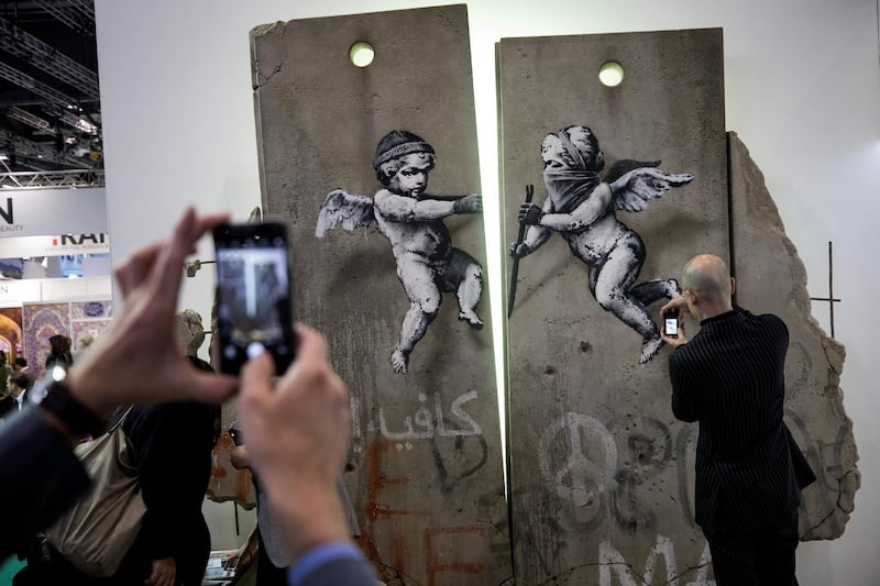 Visitors take photographs of the 'replica separation barrier' created by British street artist Banksy as it stands on display at the Palestine tourist stand at the World Travel Market at the Excel centre in London. Reuters