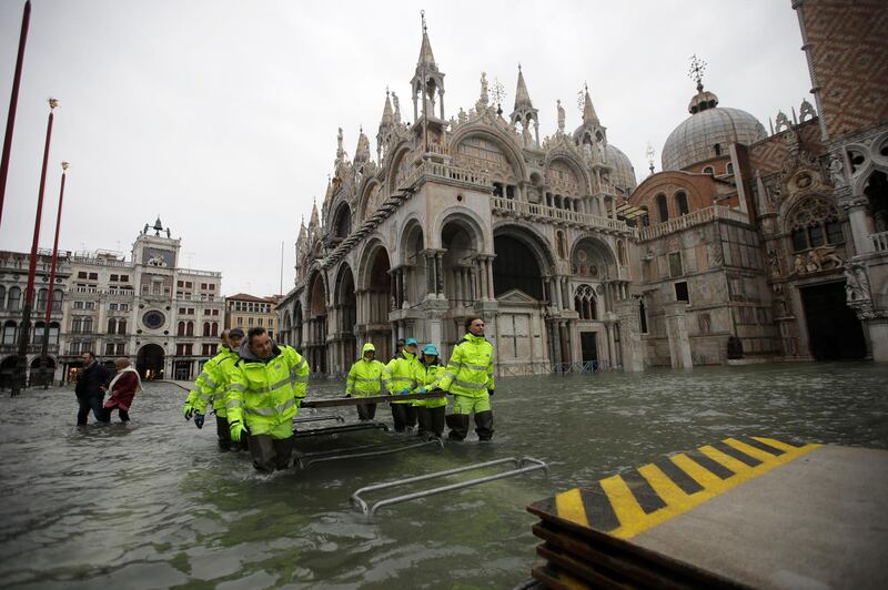 Municipality workers carry wooden boards to create a trestle bridge in a flooded St. Mark's Square at Venice. AP Photo