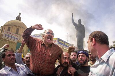 Iraqis cheer about setting a statue of former Iraqi president Saddam Hussein on fire, after American soldiers captured the area from Iraqi military control in Baghdad, on April 12, 2003. EPA