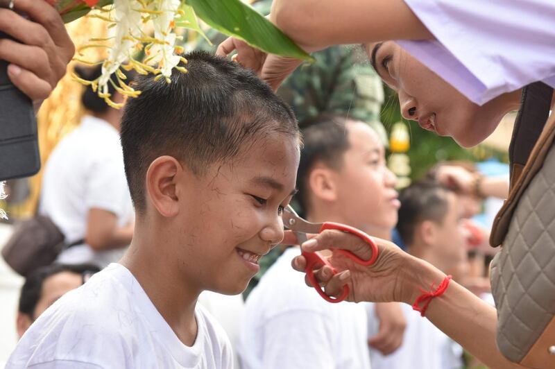 A family member cuts the hair of the rescued Thai boy Chanin Wiboonrungrueang. AFP