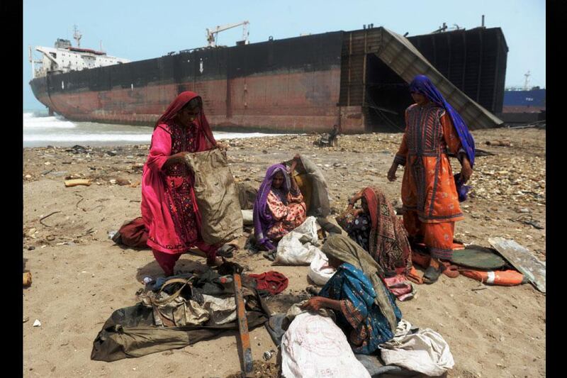A woman's work: Pakistani women empty sacks with small scrap metal pieces they picked up on the shore near where boats have been beached and dismantled.