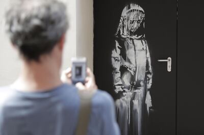 (FILES) In this file photo taken on June 25, 2018 a man takes a photograph of an artwork by street artist Banksy in Paris on a side street to the Bataclan concert hall where a terrorist attack killed 90 people on Novembre 13, 2015. The stolen Banksy work has been found in Italy, AFP reports on June 10, 2020.  - RESTRICTED TO EDITORIAL USE - MANDATORY MENTION OF THE ARTIST UPON PUBLICATION - TO ILLUSTRATE THE EVENT AS SPECIFIED IN THE CAPTION
 / AFP / Thomas SAMSON / RESTRICTED TO EDITORIAL USE - MANDATORY MENTION OF THE ARTIST UPON PUBLICATION - TO ILLUSTRATE THE EVENT AS SPECIFIED IN THE CAPTION
