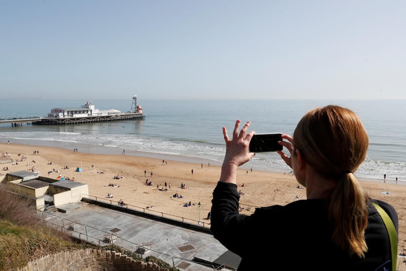 A woman takes a picture of Bournemouth Pier in the spring sunshine. Reuters