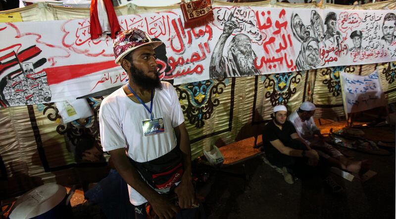 epa03805909 A Muslim Brotherhood member stands guard during a protest near Rabaa al-Adawiya mosque in Cairo, Egypt, 28 July 2013. Egyptian authorities on 26 July ordered ousted president Mohammed Morsi to be detained for 15 days pending further investigations on charges of conspiring to carry out "hostile acts" in the country, reported state-run newspaper al-Ahram online. Morsi's backers and opponents were, meanwhile, rallying for rival demonstrations across the country, mainly in Cairo. Scores of anti-Islamist activists were turning out at central Cairo's Tahrir Square in response to a call made by army chief Abdel-Fattah al-Sissi, who engineered Morsi's ouster.The Islamist group's followers were also on 26 July flocking to the area of Rabaa al-Adawiya, in north-eastern Cairo, joining many others who have been camping there for weeks to protest what they call a military coup against Morsi, Egypt's first democratically elected president.  EPA/MOHAMMED SABER *** Local Caption ***  03805909.jpg