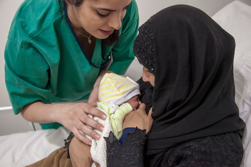 A midwife guides Naeema through the breastfeeding process with her baby