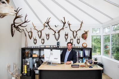 Najjar at his desk with hunting trophies, including a stuffed and mounted Chinese water deer, right. Rob Greig for The National
