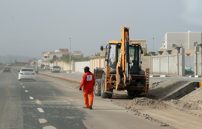 Workers clear mud from the roads after recent floods in Kalba. 

