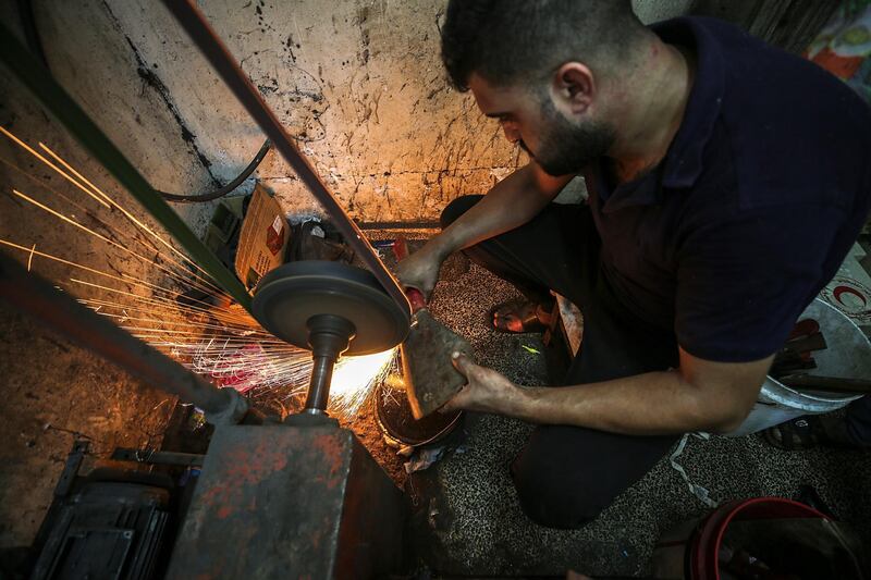 A Palestinian man sharpens a knife that will be used to slaughter cattle or cut meet during Eid Al Adha, in Gaza City.  EPA