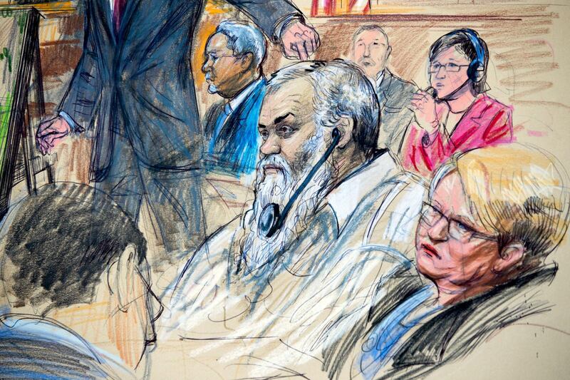 FILE - This Oct. 2, 2017, file courtroom sketch depicts Ahmed Abu Khattala listening to a interpreter through earphones during the opening statement by assistant U.S. attorney John Crabb, second from left, at federal court in Washington, in the trial presided by U.S. District Judge Christopher Cooper. Defense attorney Jeffery Robinson, sits behind Crabb in a light blue suit and Michelle Peterson, also a member of the defense team, is at far right. Ahmed Abu Khattala was sentenced June 27, 2018, to 22 years in prison for his role in the 2012 attacks on U.S. compounds in Benghazi, Libya, that killed four Americans, including Ambassador Chris Stevens.(Dana Verkouteren via AP)