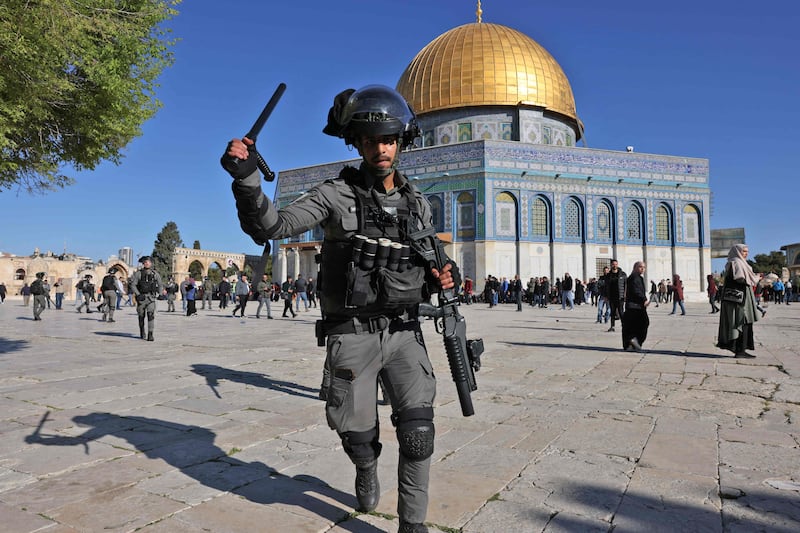 A member of the Israeli security forces lifts his baton in front of the Dome of the Rock mosque. Witnesses said Palestinian protesters threw stones at Israeli forces, who fired rubber bullets. AFP
