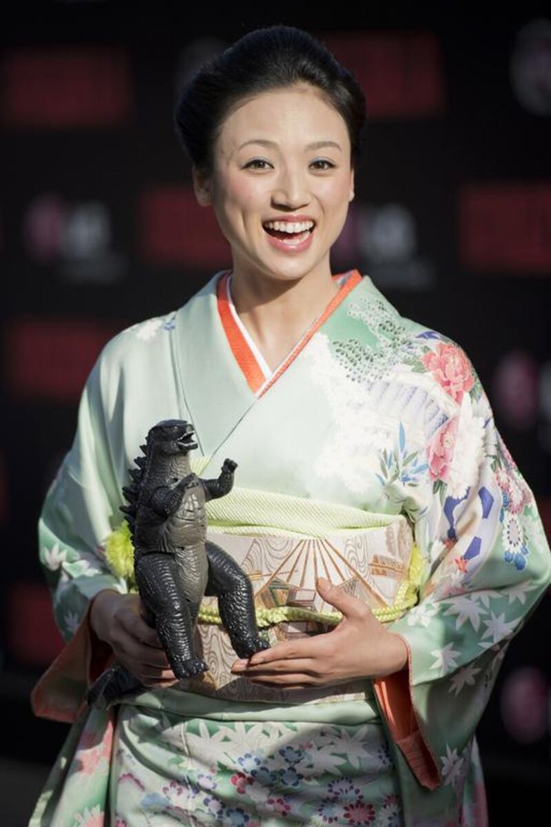 A representative from Toho wearing a traditional Japanese dress holds a plastic model of Godzilla at the Los Angeles movie premiere of Godzilla on May 8, 2014 at the Dolby Theatre in Hollywood, California. Robyn Beck / AFP