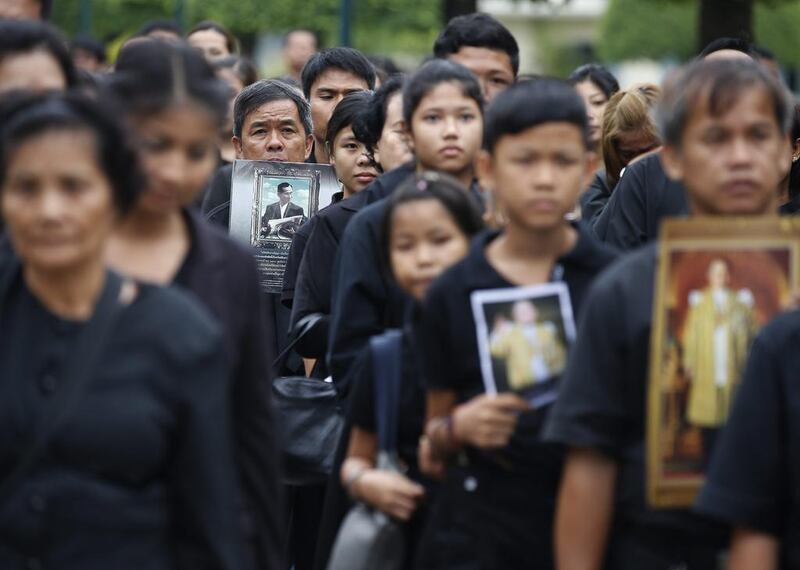 Mourners bear portraits of the late king as they gather to pay their respects at the Grand Palace in Bangkok. Narong Sangnak / EPA