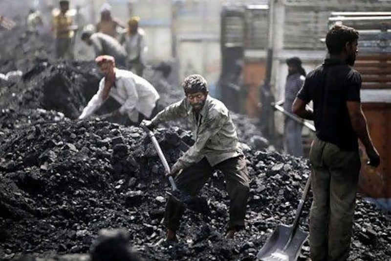 Labourers load coal onto trucks at a coal depot on the outskirts of Jammu, India. India's national auditor said the Indian government lost huge sums of money by selling coal fields to private companies without competitive bidding.