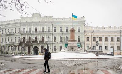 A citizen crosses a street in Odesa as a Ukrainian flag flies. Getty 
