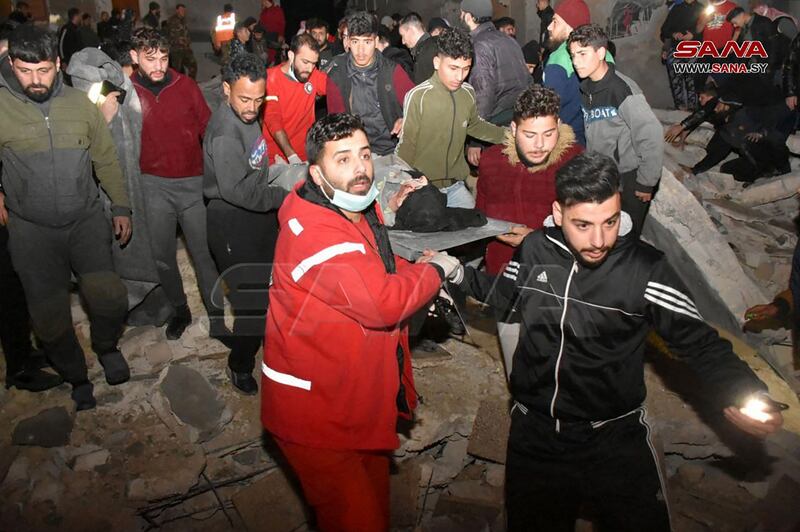 Rescuers carry a victim pulled out from under the rubble of an eight-storey building. AFP