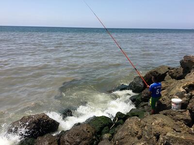 A resident of the southern Beirut neighborhood of Ouzai fishes meters from where raw sewage enters the Mediterranean, turning the water grey. Residents say the problem has existed for years. June 28, 2018. 