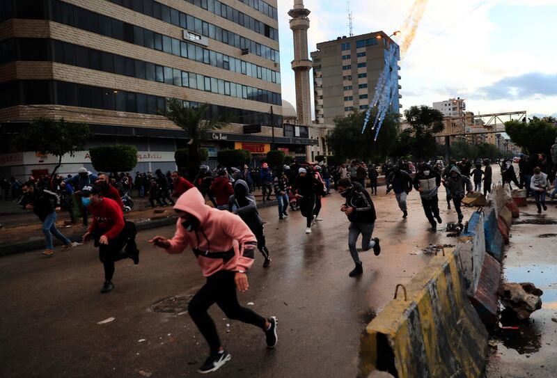 Protesters run from tear gas canisters during a protest against deteriorating living conditions and strict coronavirus lockdown measures in Tripoli, north Lebanon. AP