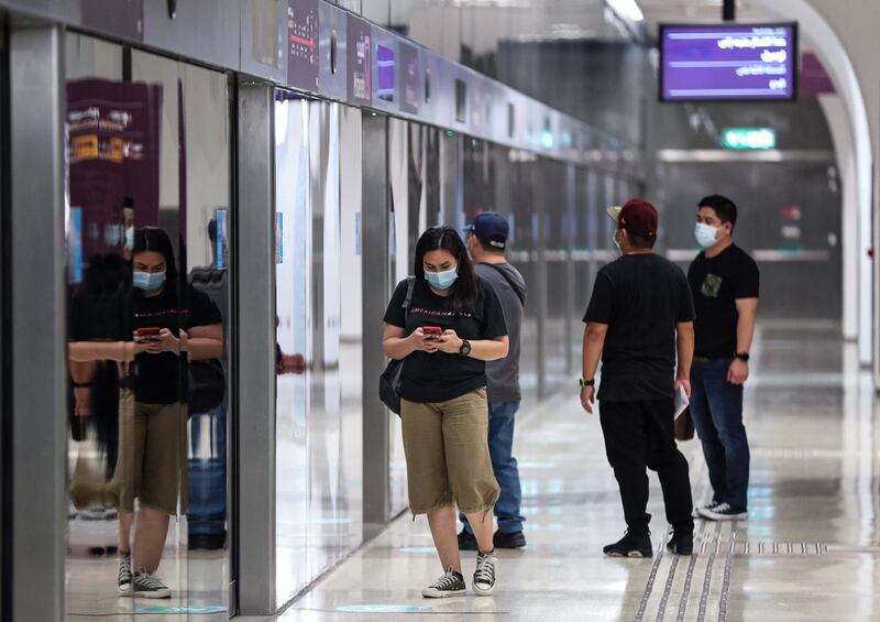 Mask-clad passengers stand along the train platform at a station in Doha, Qatar. AFP